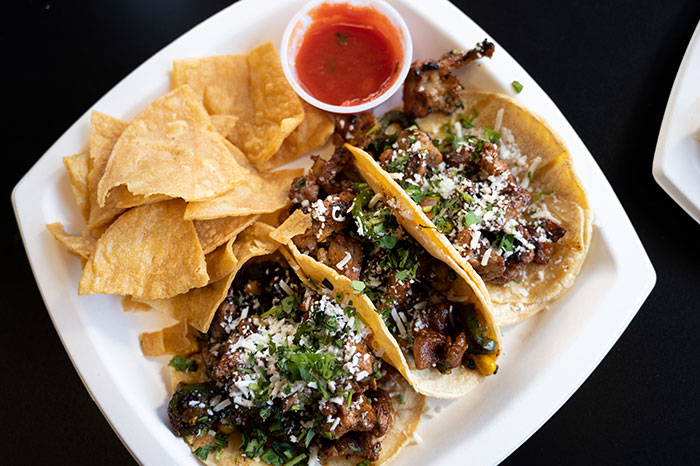three authentic tacos with tortilla chips and hot sauce from burrito bros